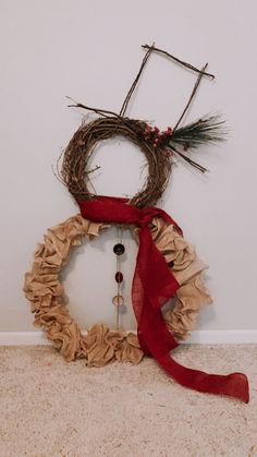 a wreath made out of twigs with a red ribbon around it and a clock on the wall