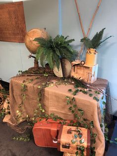 a table topped with lots of luggage covered in greenery next to a wooden sign