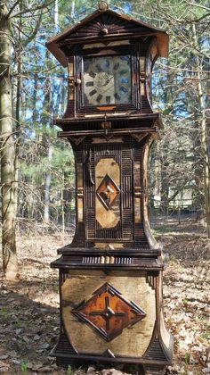 an old clock tower sitting in the middle of a forest