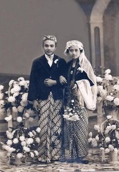 an old black and white photo of two people dressed in ethnic garb standing next to each other