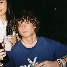 two people are holding drinks and looking at the camera