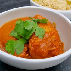 two white bowls filled with food and garnished with cilantro