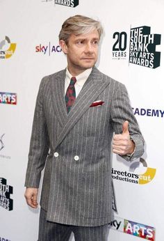 a man in a suit and tie giving the thumbs up sign at an awards event