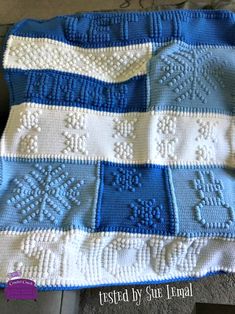 a blue and white crocheted blanket on the floor