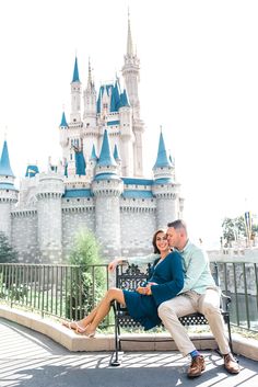 a man and woman sitting on a bench in front of a castle at disney world