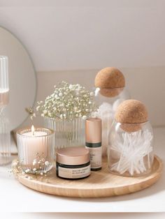 a wooden tray topped with bottles and candles next to a mirror on top of a table