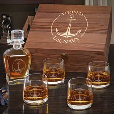 four whiskey glasses sitting next to a wooden box with an anchor on the front and bottom