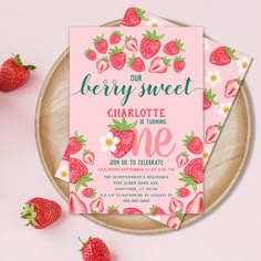 two strawberry themed baby shower cards on a plate with strawberries