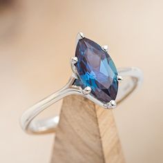 a blue diamond ring sitting on top of a wooden stand