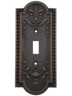 an ornate light switch plate cover in bronze and black with intricate designs on the front