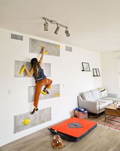 a woman climbing up the side of a wall with yellow safety equipment on her feet