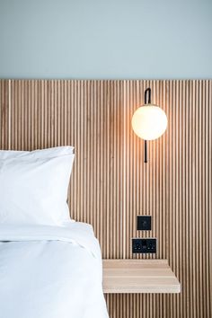 a white bed sitting next to a night stand with a lamp on top of it