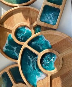 three wooden trays with blue and green designs on them, one has the letter a in it