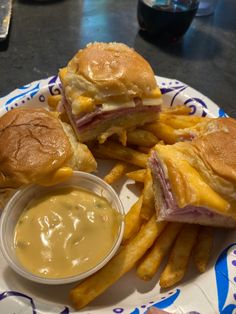 two sandwiches and french fries are on a plate with mustard sauce in front of them