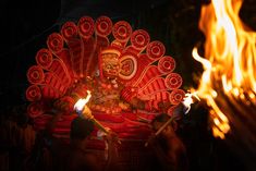 a person holding torches standing in front of a fire