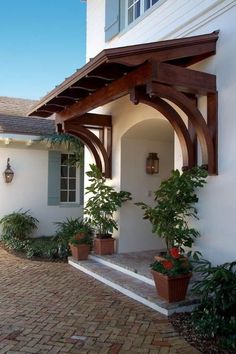 an outside view of a house with potted plants on the front porch and attached awning