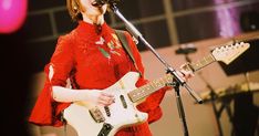 a woman singing into a microphone while holding a guitar