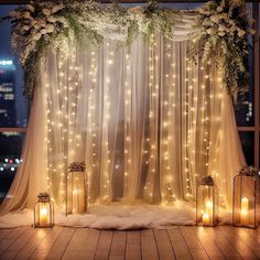 a wedding stage decorated with white flowers and fairy lights, surrounded by sheer drapes