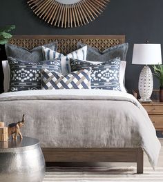 a bed with blue and white pillows on top of it next to a wooden headboard