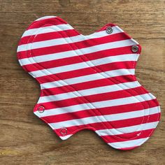 a red and white striped oven mitt sitting on top of a wooden table