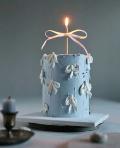 a blue cake with white frosting and a lit candle