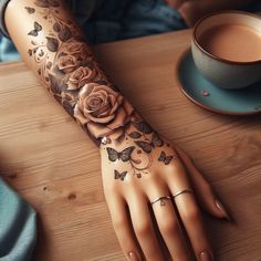 a woman's arm with flowers and butterflies on it, next to a cup of coffee