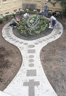 people are sitting in the middle of a garden with flowers and plants growing on it