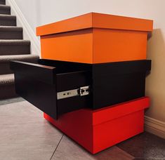 an orange and black box sitting on the ground next to some stairs with a hand rail