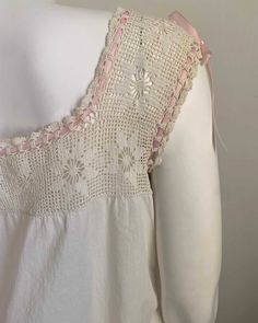 the back of a white dress with pink trimmings and crocheted lace