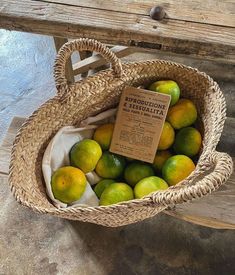 a basket filled with lots of green and yellow fruit on top of a wooden bench