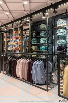 a clothing store with lots of shirts hanging on the racks in front of glass walls