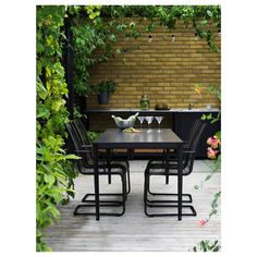 an outdoor dining table with four chairs and two wine glasses on it in front of a brick wall