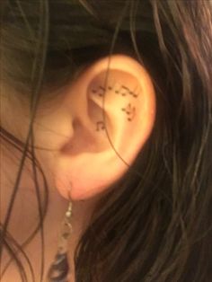 a woman's ear with the word love written on it and two small stars behind her ear