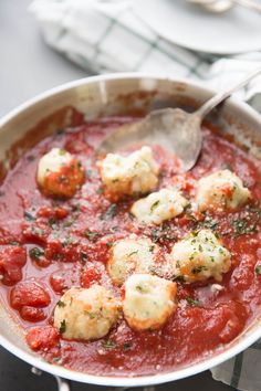 a pan filled with meatballs covered in sauce and garnished with parmesan cheese