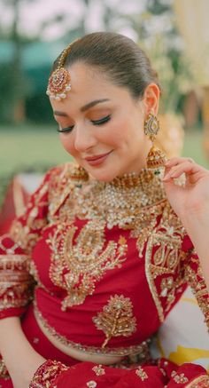 a woman in a red and gold outfit smiles while sitting down with her hands on her hips