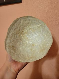 a person is holding up a large ball of dough