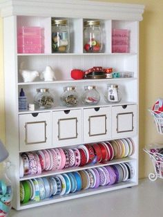 a white book shelf filled with lots of different colored ribbons and other crafting supplies