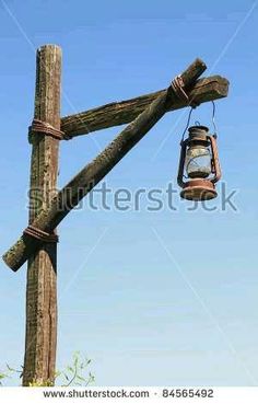 an old fashioned lantern hanging from a wooden pole