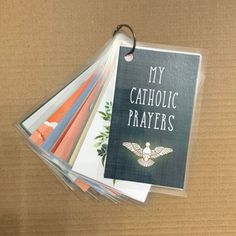 a bunch of cards that are sitting on top of a cardboard box with the words my catholic prayer written on them