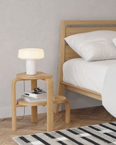 a bedroom with a bed, nightstand and lamp on the side table in front of it