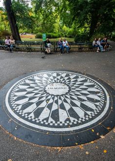 people are sitting on benches near a large mosaic in the middle of a public park