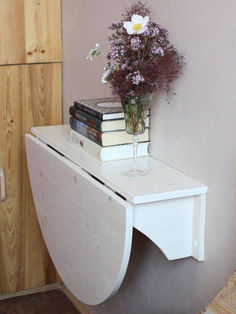 a vase filled with flowers sitting on top of a white shelf next to a book