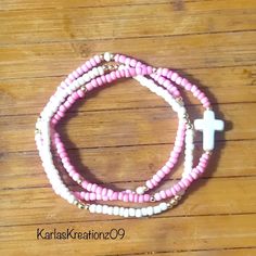 This trendy handcrafted 3-piece bracelet set is made of various shades of pink, ivory, and gold-plated seed beads along with an ivory-colored cross bead. Made with quality stretch cord.  Makes a great gift! Please measure your wrist before placing an order.  How to care for your bracelets:  Handle with care and please limit exposure to oils, water, fragrances, and chemicals.  See my other beautiful creations by visiting my store: https://karlaskreationz09.etsy.com Spiritual Pink Jewelry For Birthday, Beaded Pink Wrap Bracelet Gift, Handmade White Bracelets For Birthday, Pink Beaded Wrap Bracelet As Gift, Pink Wrap Bracelet With Round Beads For Gifts, Pink Stackable Bracelets For Birthday, Pink Stackable Bracelets For Birthdays, Adjustable Handmade Pink Rosary Bracelet, Handmade White Rosary Bracelet For Friendship