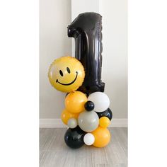 a balloon shaped like a number one sitting on top of a pile of balloons in the shape of a smiley face