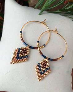 two gold hoop earrings with blue beads and hamsa hand charms on a white pillow