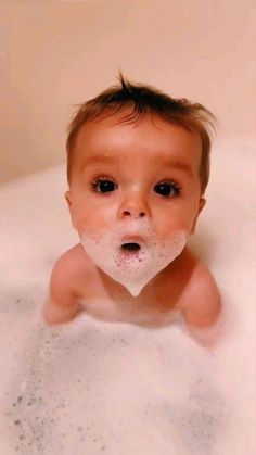 a baby is sitting in the bathtub with soap on his face