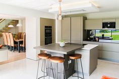 a kitchen with two stools and a center island in front of an open floor plan