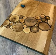 a wooden cutting board with circles and beads on the edges, sitting on a wood floor