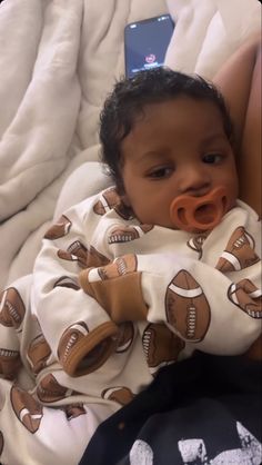 a baby laying on top of a bed wearing a pacifier in it's mouth