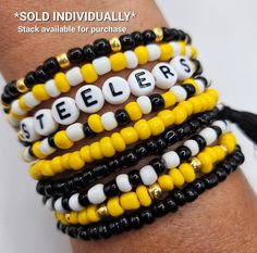 several bracelets with letters on them are shown in yellow, black and white colors